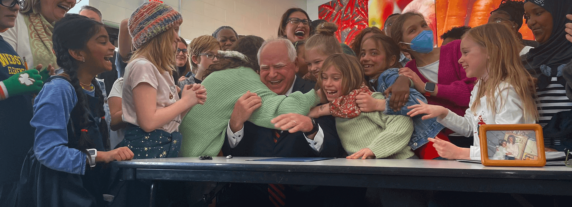 Governor Tim Walz is hugged by Minnesota public school students as he signs Universal School Meals into law.