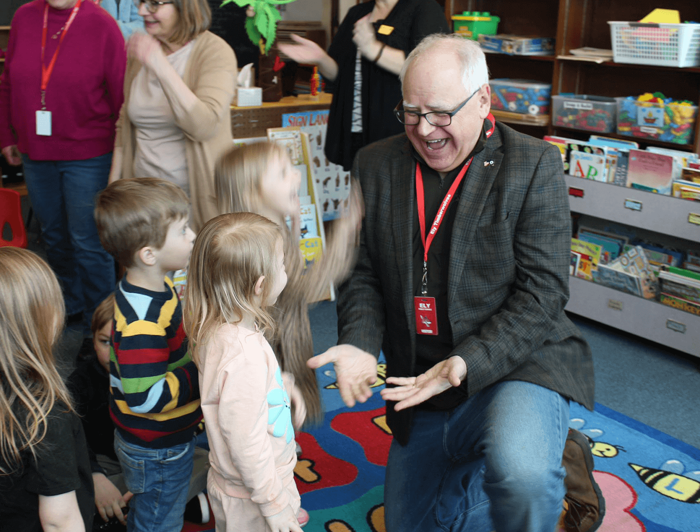 Governor Tim Walz is kneeling and offering high fives to two Minnesota public school students.